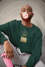 Green sweatshirt worn, front "Happy birthday" cake and candle graphic, crew neck.