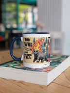 Navy ceramic mug on a book, featuring bear, flames, and “TOO WILD FOR HERBAL TEA.”