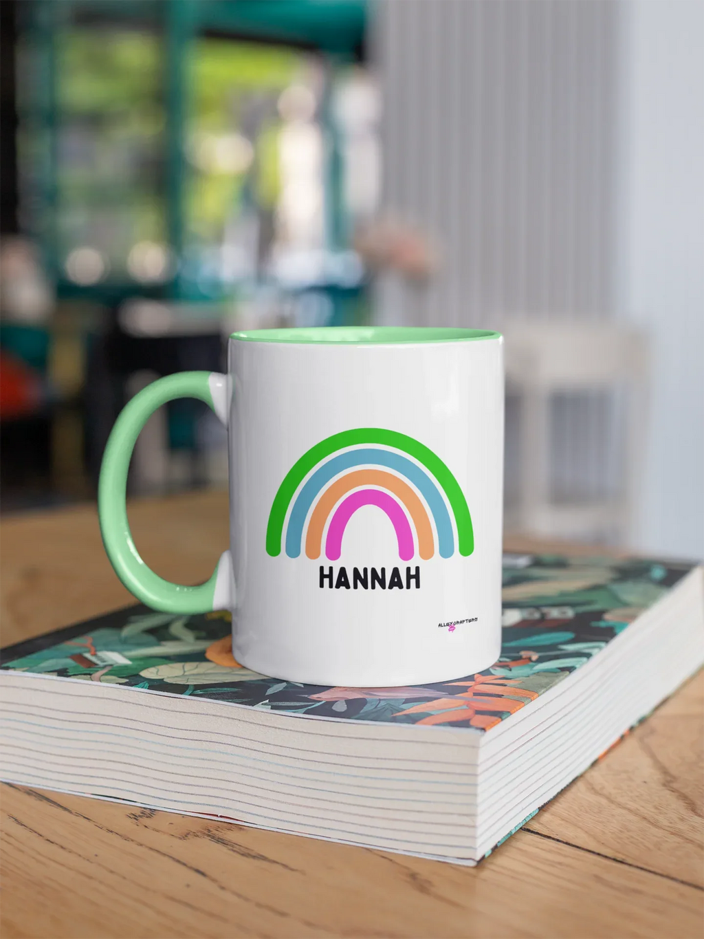 Personalised rainbow mug with HANNAH name, white body and green handle, rainbow graphic