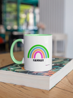 Personalised rainbow mug with HANNAH name, white body and green handle, rainbow graphic