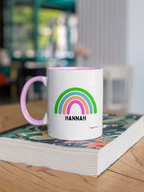 Personalised rainbow mug with HANNAH name, white body and purple handle, rainbow graphic