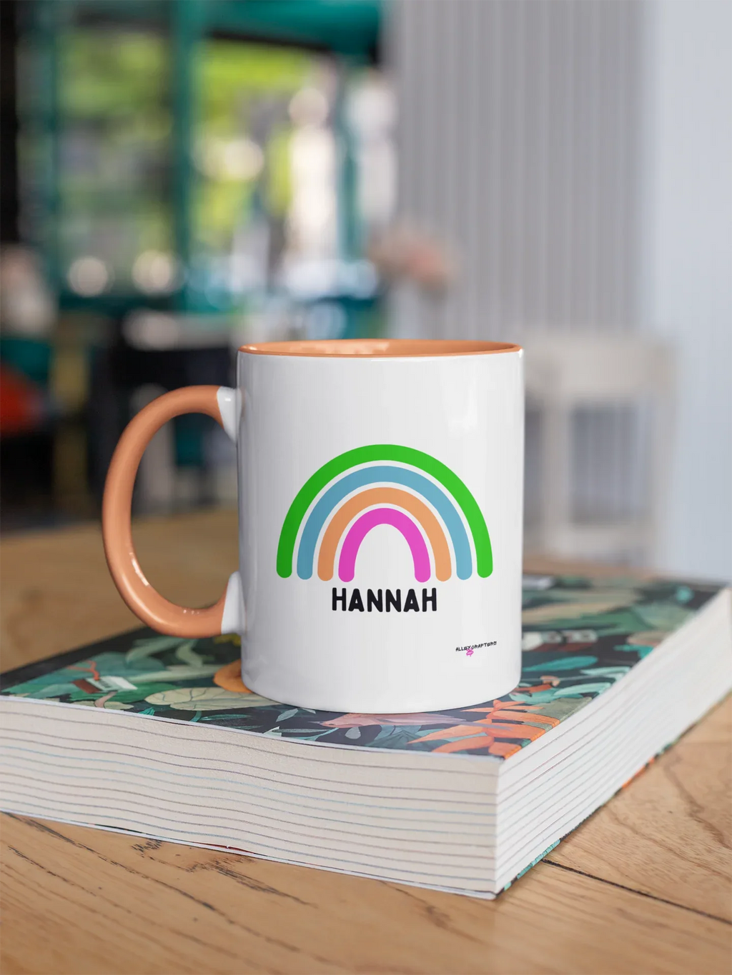 Personalised rainbow mug with HANNAH name, white body and orange handle, rainbow graphic