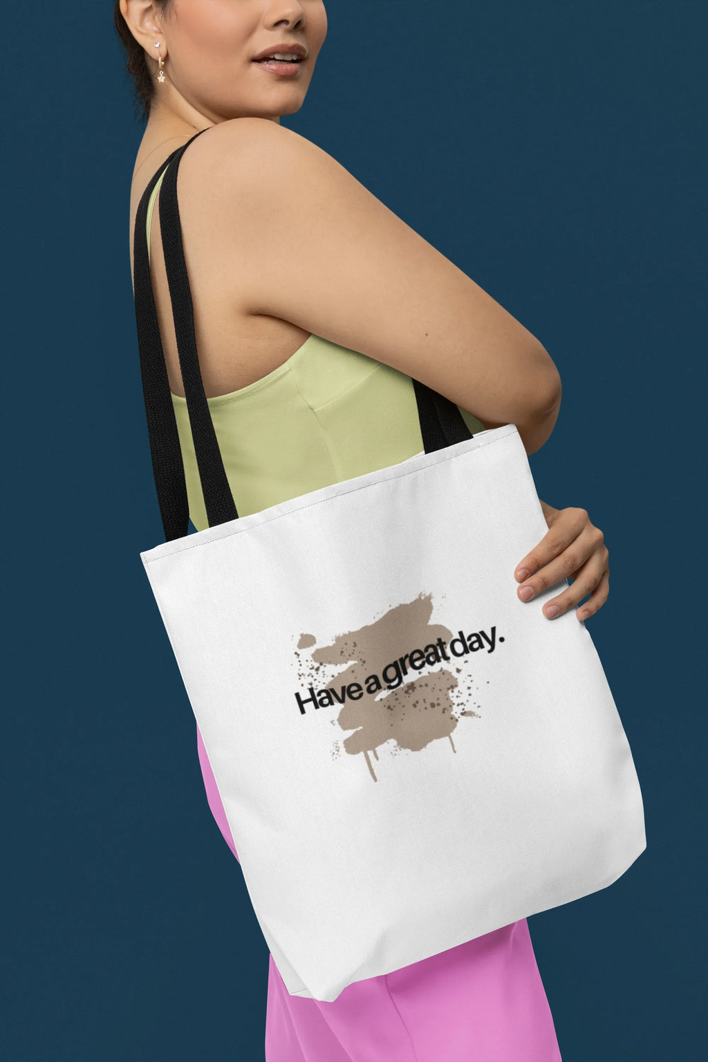 White tote bag with brown 'Have a great day' print, held in hand by straps