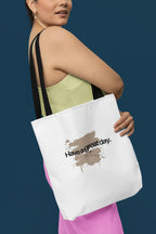 White tote bag with brown 'Have a great day' print, held in hand by straps