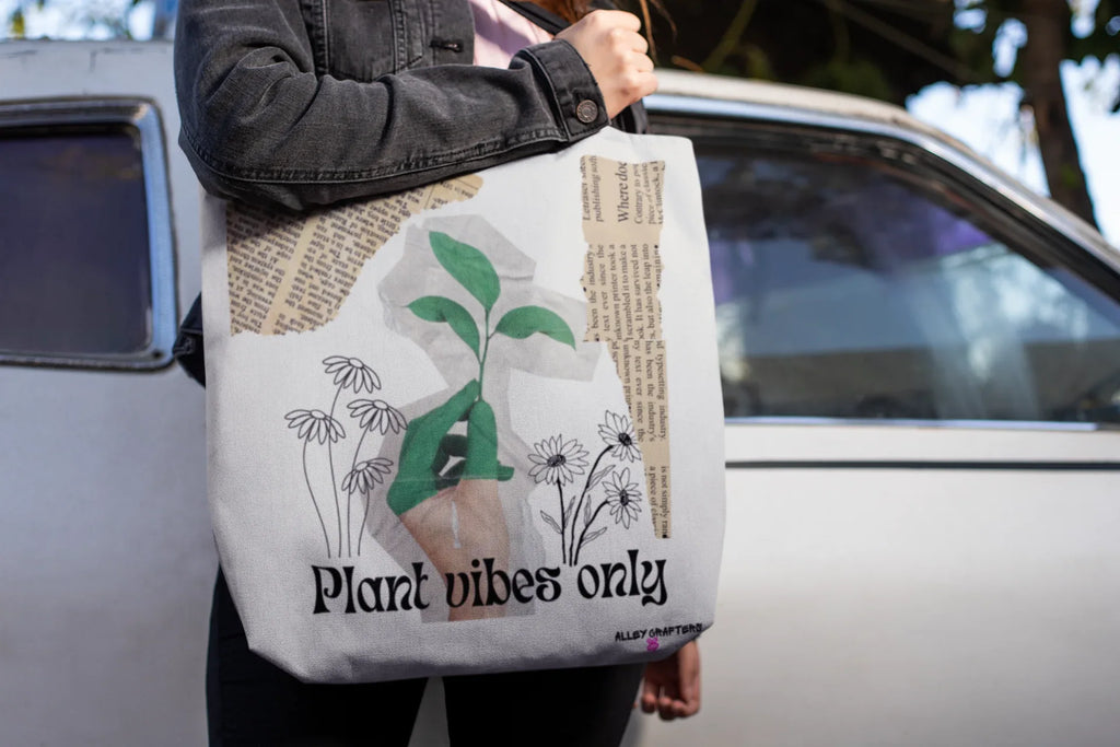 White tote bag with green plant artwork and 'Plant vibes only' logo, held by hand