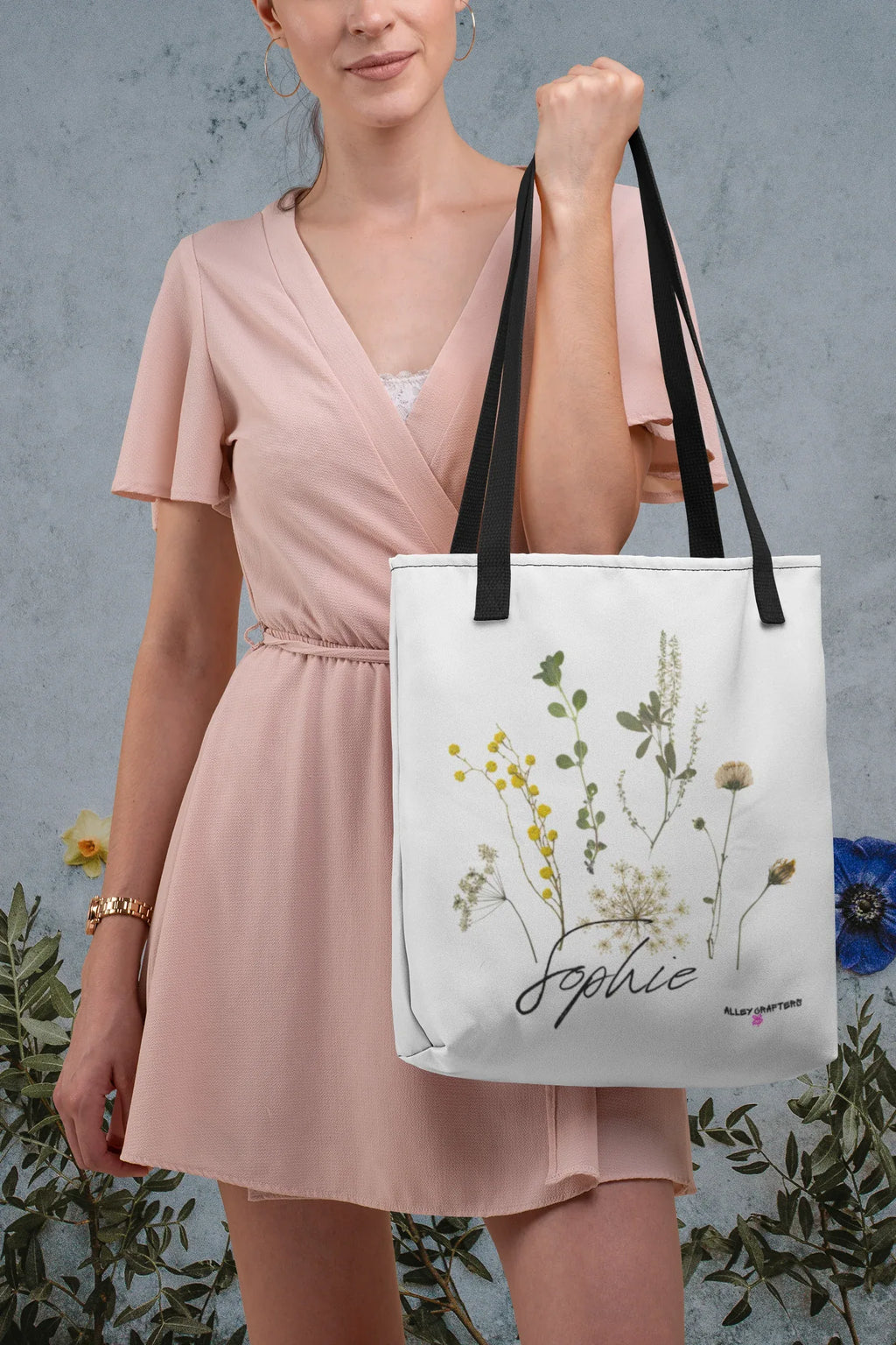 White canvas tote bag with black handle straps and botanical print, cursive "Sophie"