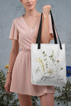 White canvas tote bag with black handle straps and botanical print, cursive "Sophie"