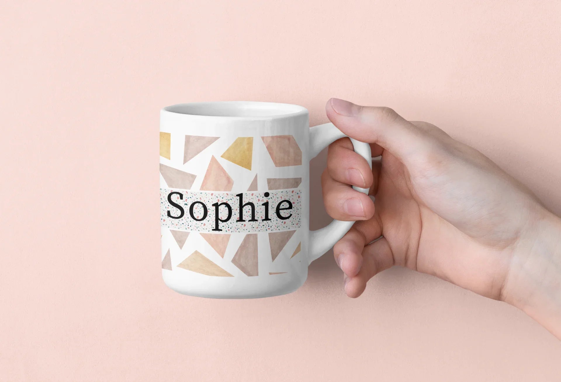 White mug with geometric triangles and name Sophie, held by a hand