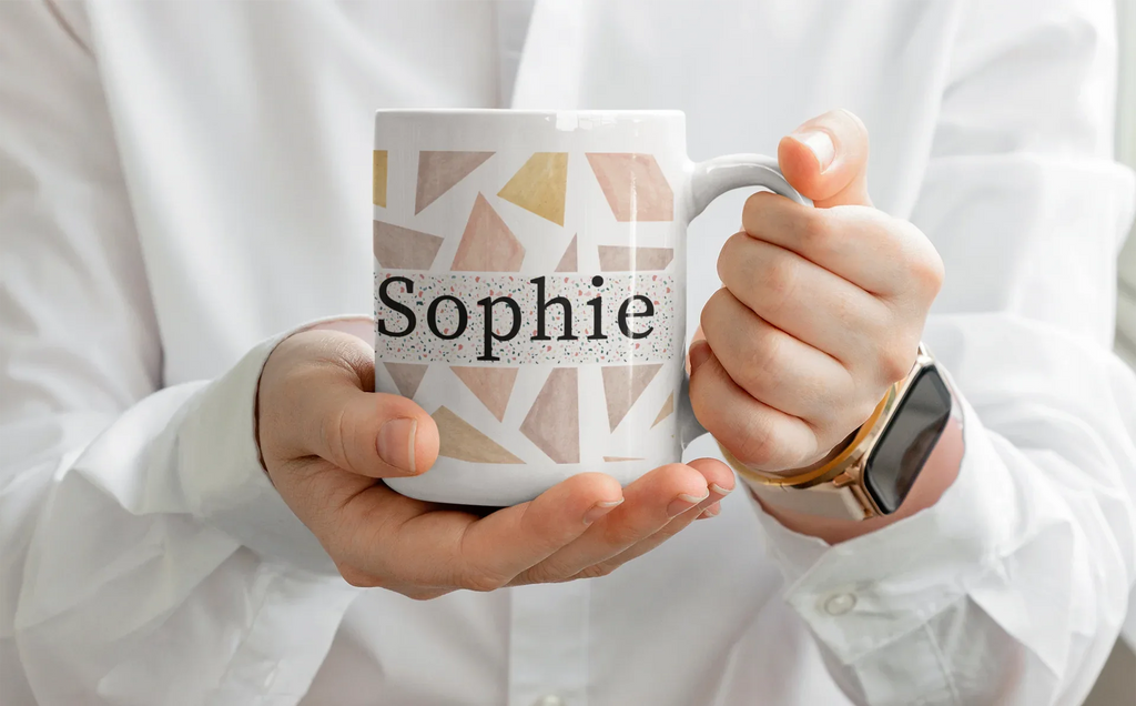 White mug with geometric triangles and name Sophie, held in hands