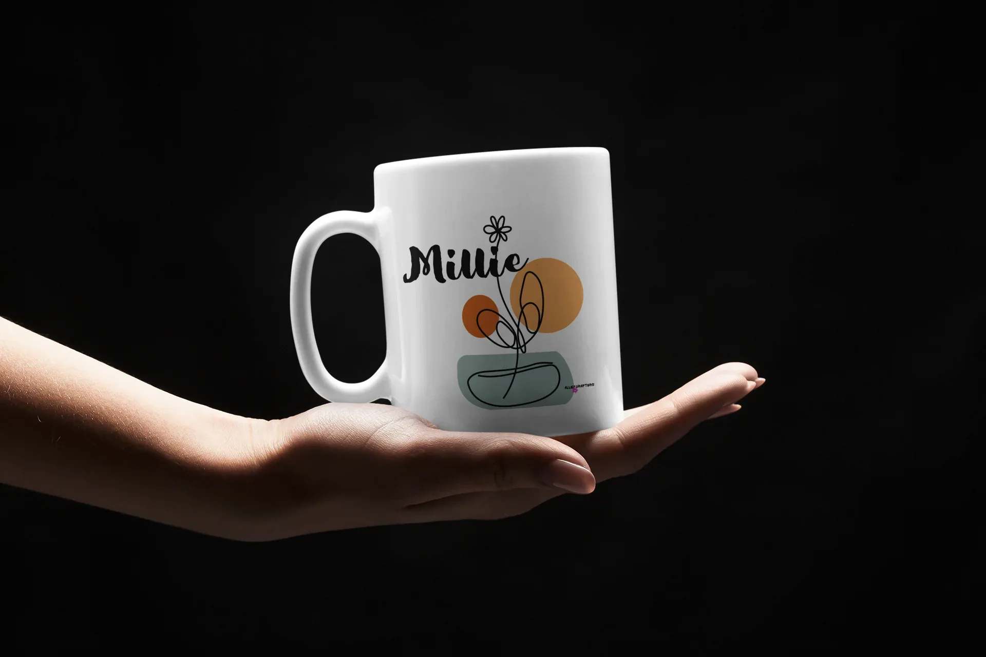 White ceramic mug with Millie name and floral pot graphic, held in hands