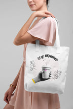 White canvas tote bag with pink handles and Stay Grounded coffee cup graphic on person