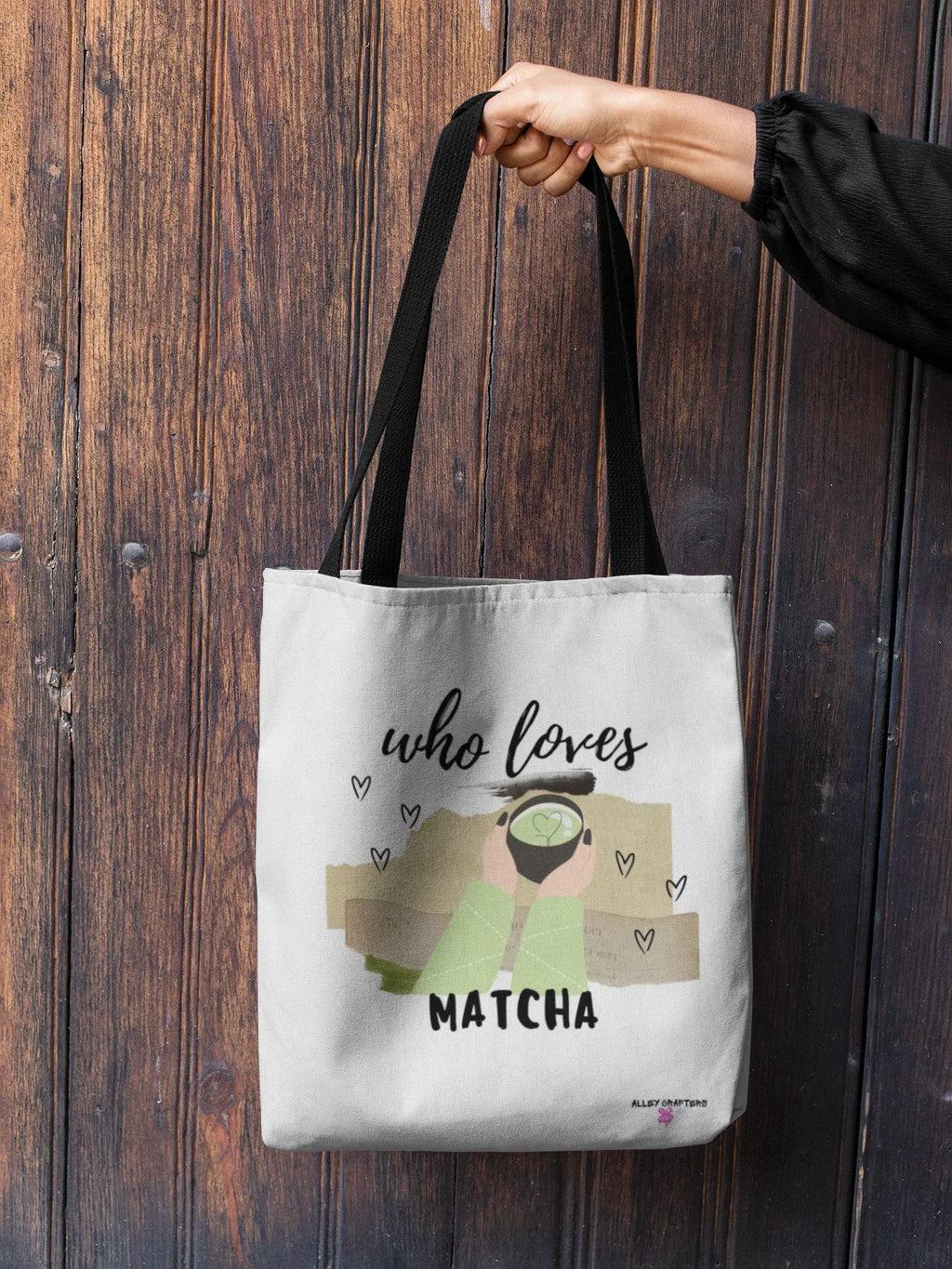 White tote bag with “who loves MATCHA” print, held by black top handles.