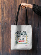 White canvas tote bag with long black handles, front quote logo with colorful lines