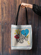 Light canvas tote bag front with blue trim and black handles, hanging from hand