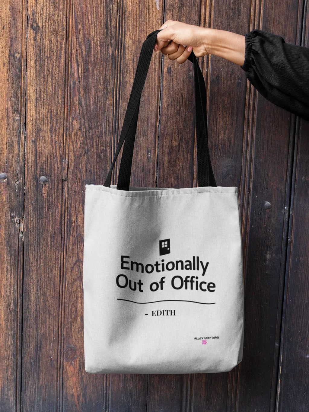 White canvas tote bag with top handles and black printed front slogan, held by strap