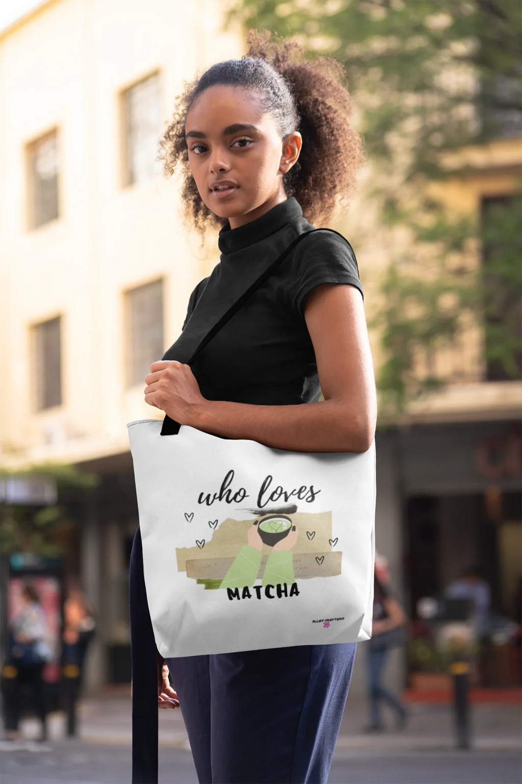 White tote bag on model, featuring “who loves MATCHA” illustration centered on front.