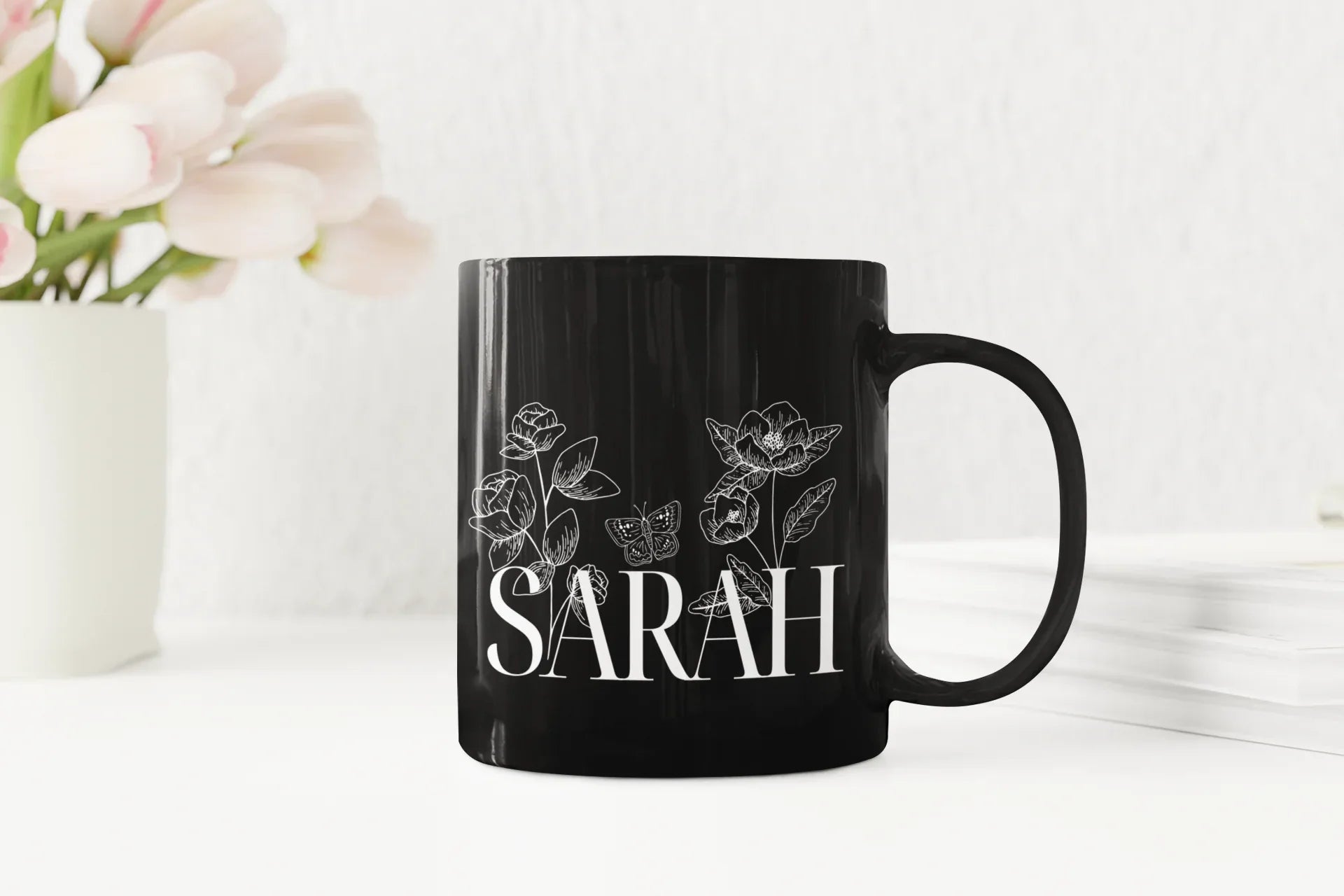 Black ceramic mug with floral line art and name SARAH on front