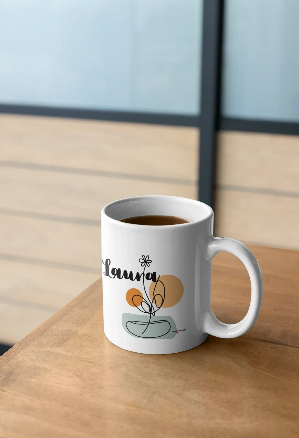 White ceramic mug with personalized Laura name and floral swirl bowl graphic on front.