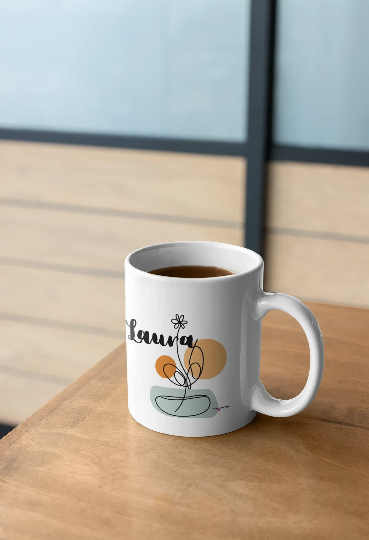 White ceramic mug with personalized Laura name and floral swirl bowl graphic on front.