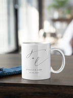 White ceramic mug with monogram j + l and date 23.06.2024, on wooden surface.