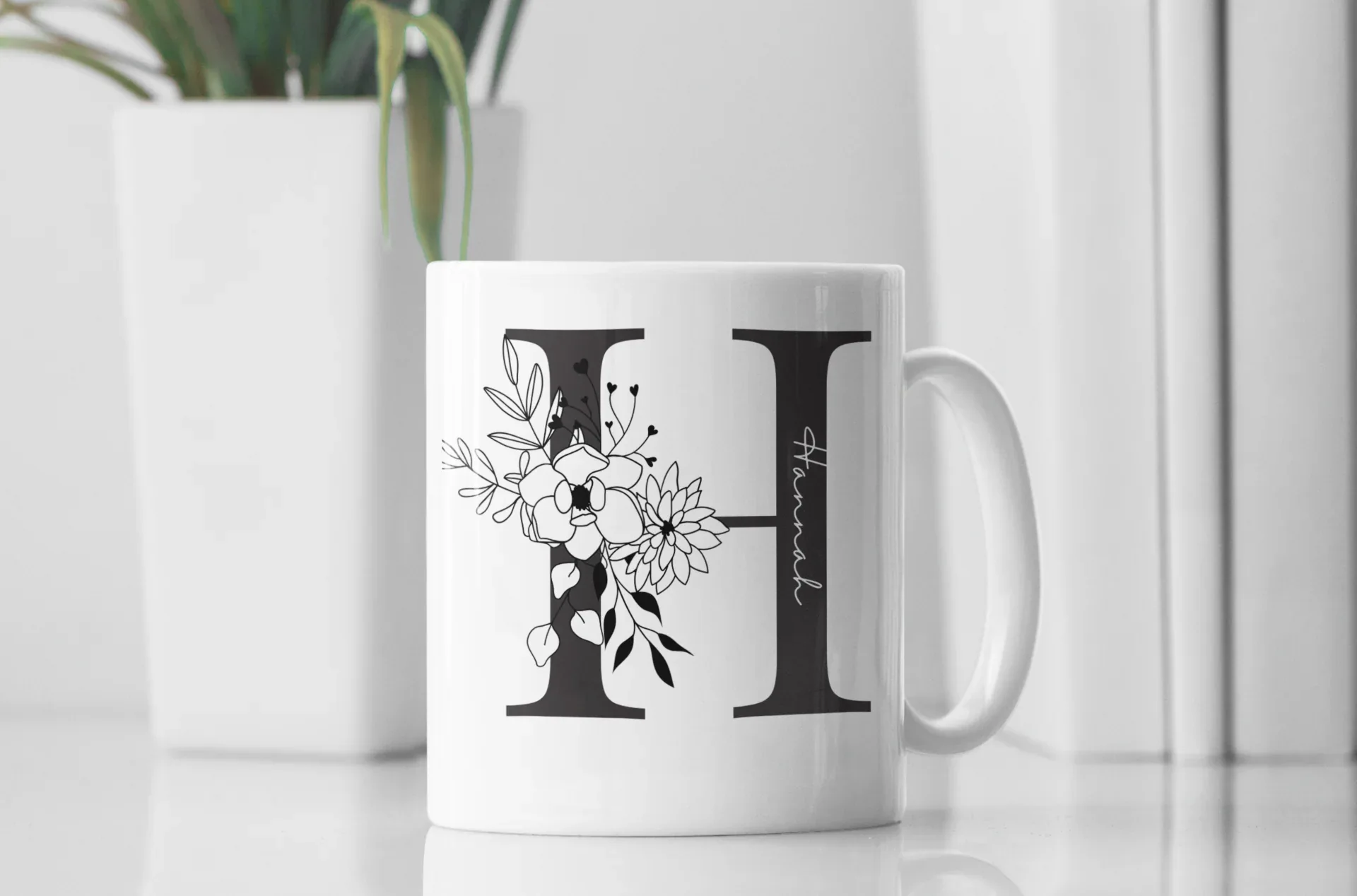 White mug with black letter I and floral line art, large handle on right