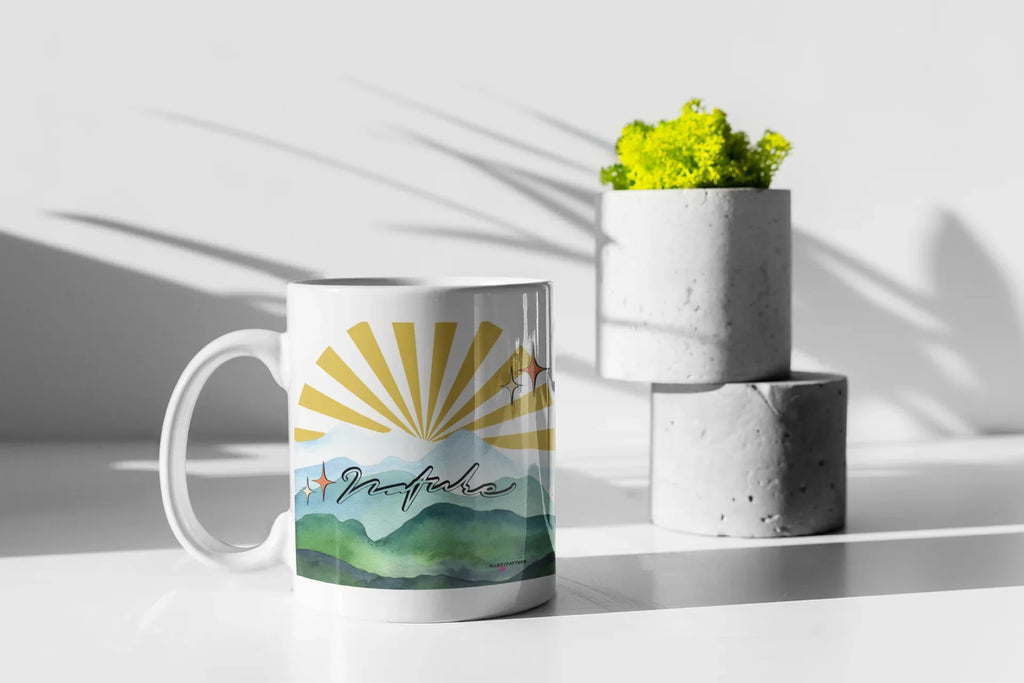 White coffee mug with sunrise mountain landscape print, handle on left side