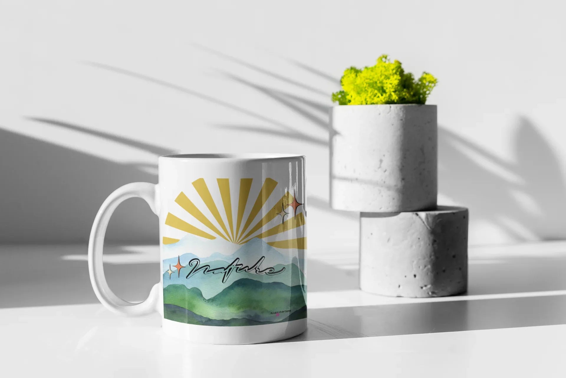 White coffee mug with sunrise mountain landscape print, handle on left side