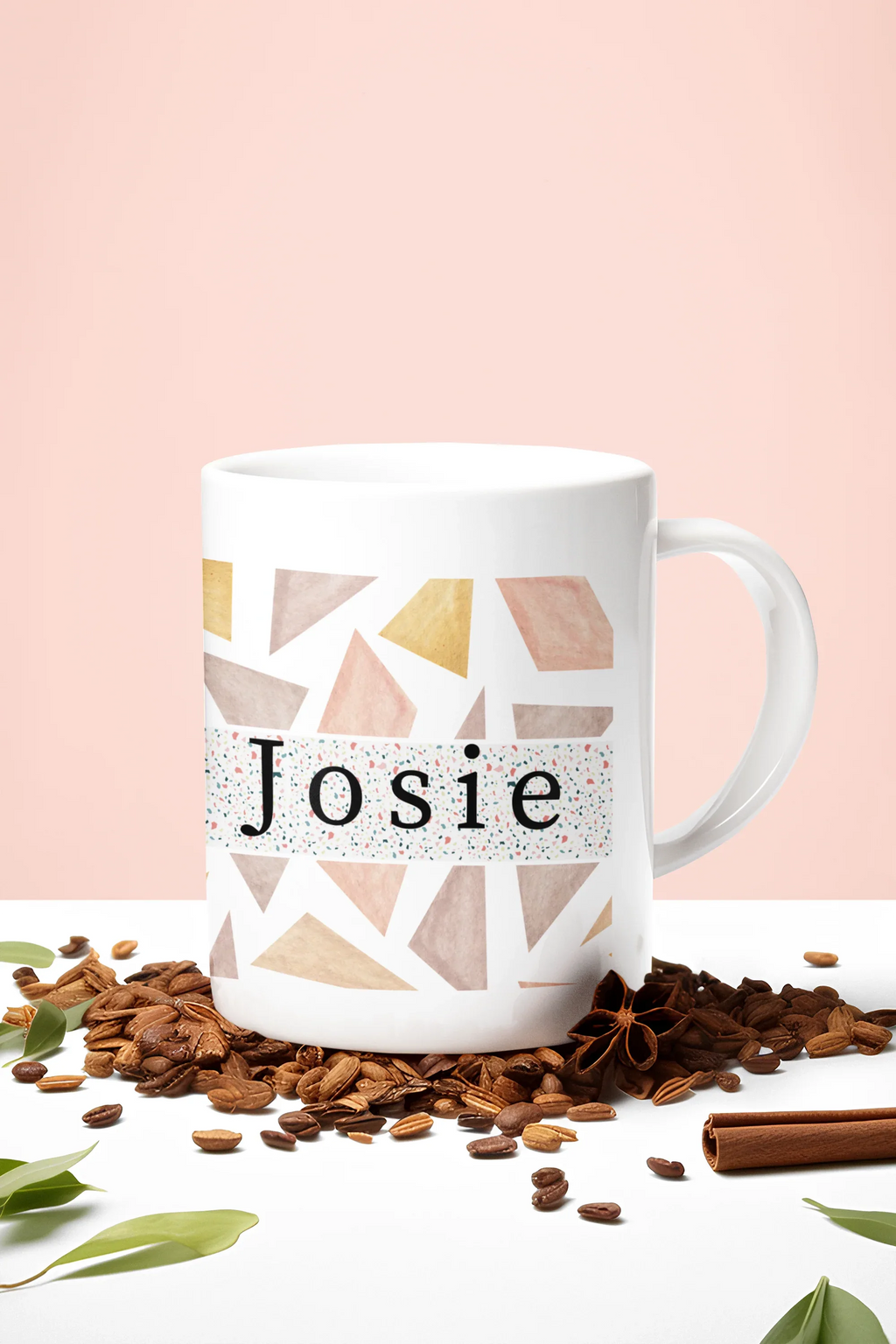 White mug with geometric triangles and name Josie, with coffee beans around it