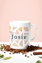 White mug with geometric triangles and name Josie, with coffee beans around it