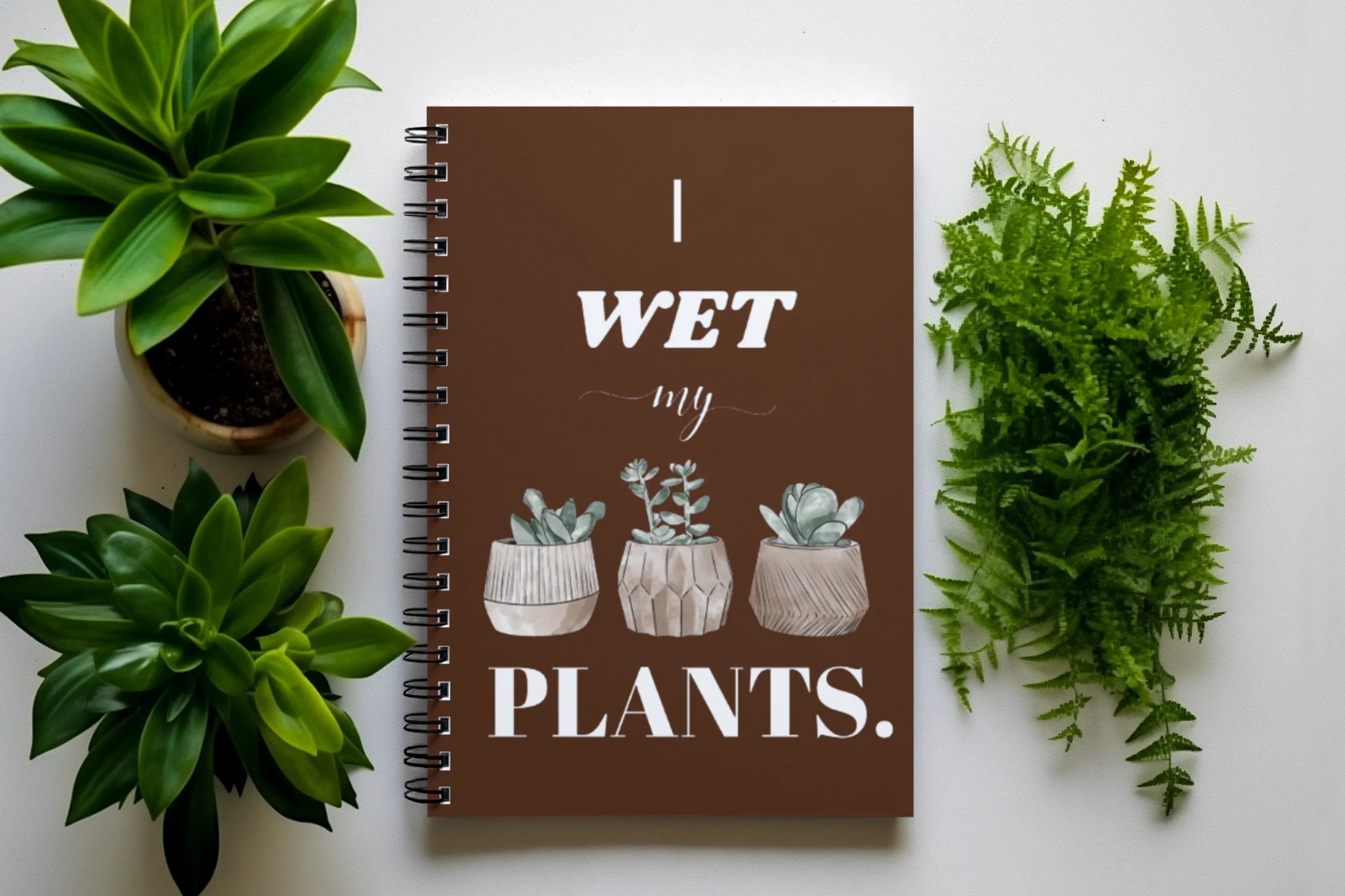 A5 spiral notebook, brown cover with “I wet my plants” text and succulent pot illustrations.