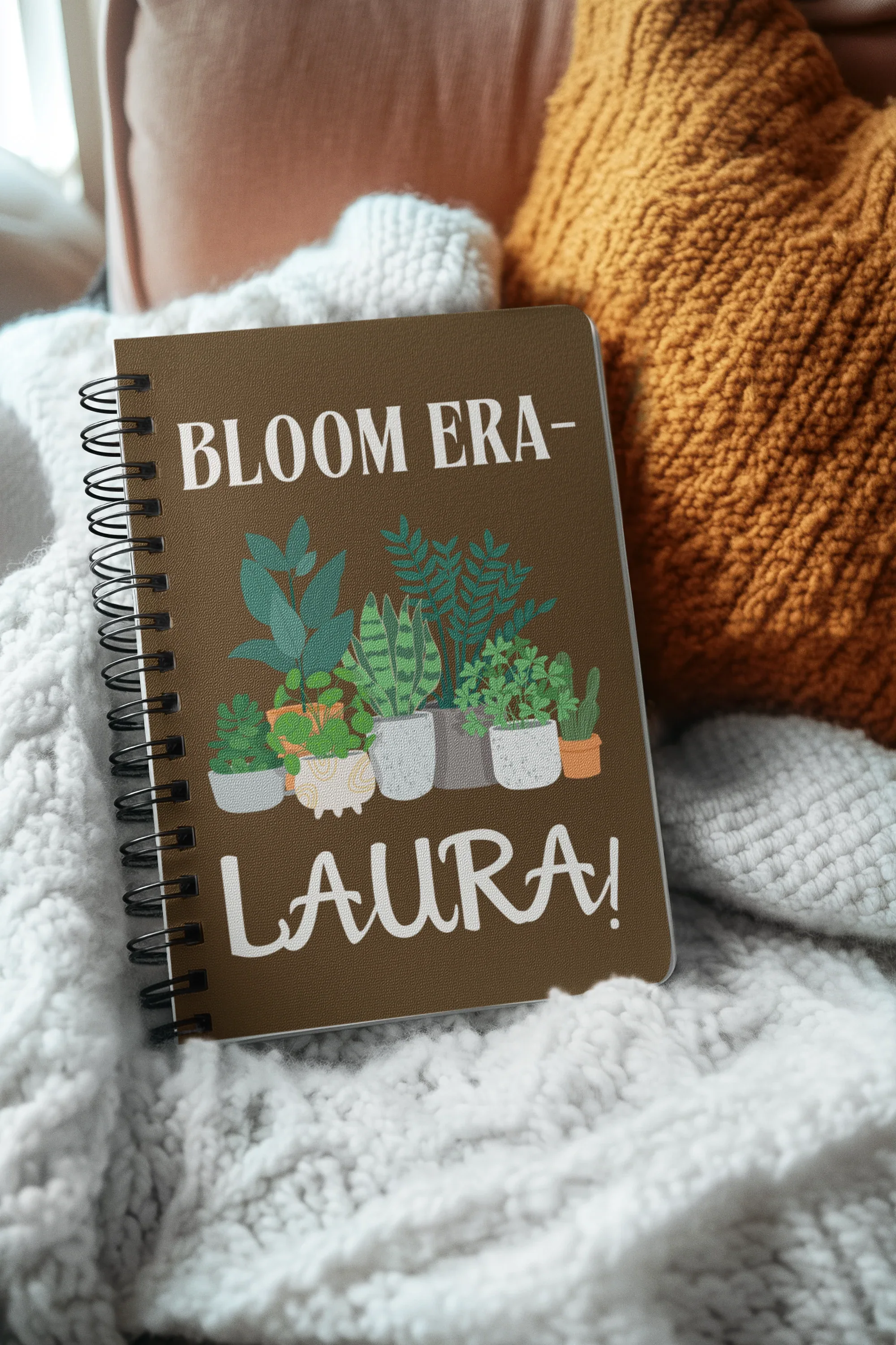 Personalised A5 lined notebook with dark brown cover, floral pots illustration and name LAURA.