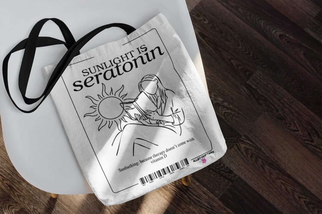 White tote bag with black graphic print of a sun and seated figure