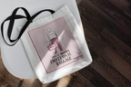 White canvas tote bag with pink graphic panel and black shoulder strap.