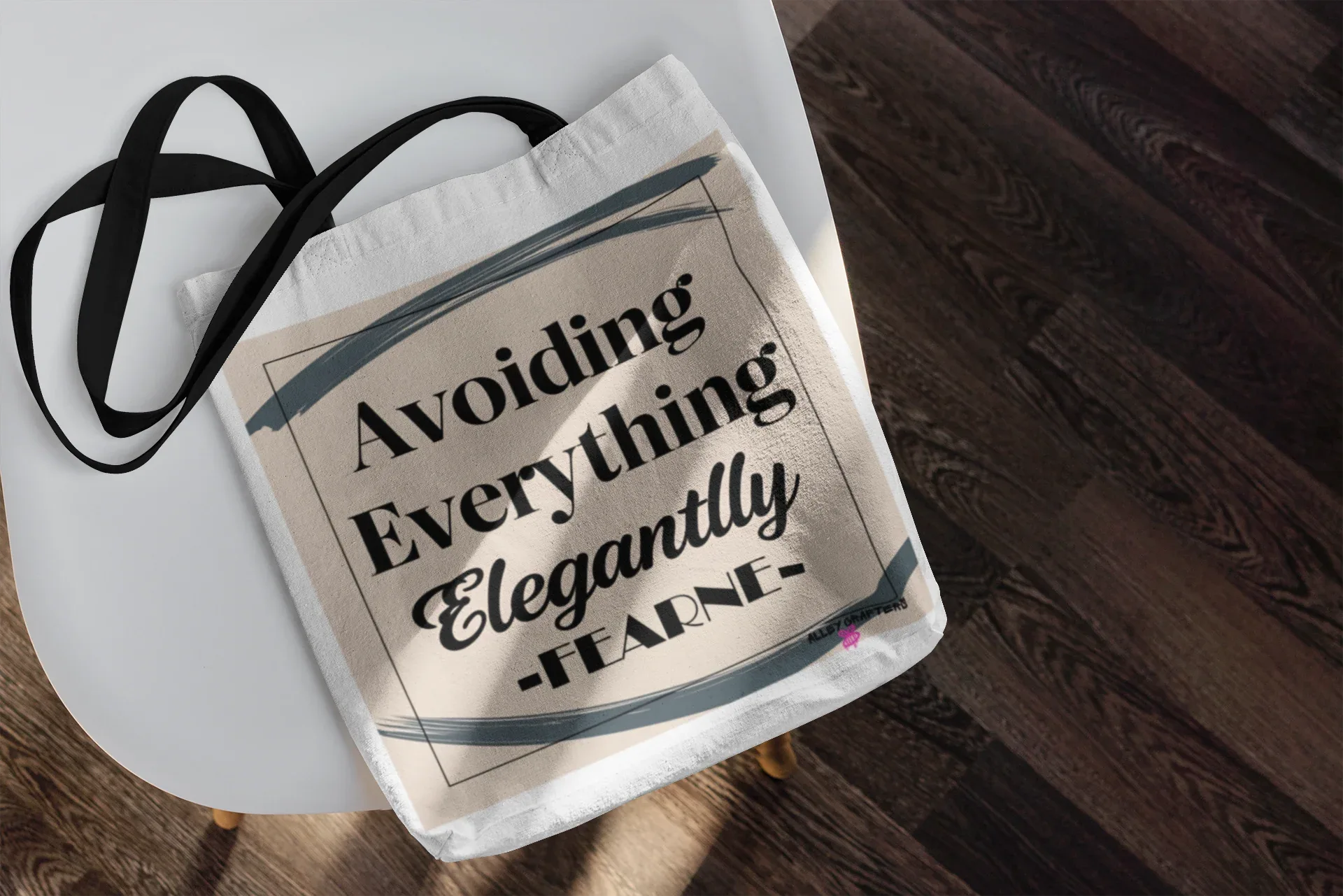 White canvas tote bag with "Avoiding Everything Elegantly" print and black strap