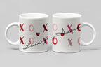 Two white ceramic mugs with red XO hearts and “Love” script, front view