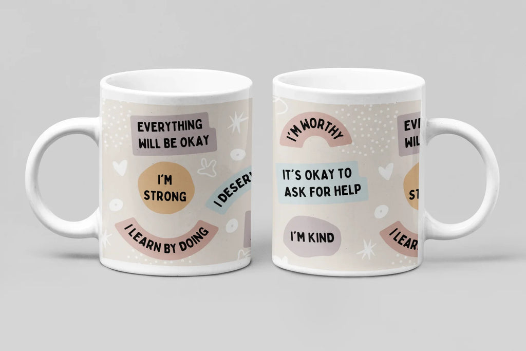 Two white ceramic mugs with pastel circular designs and uplifting message text