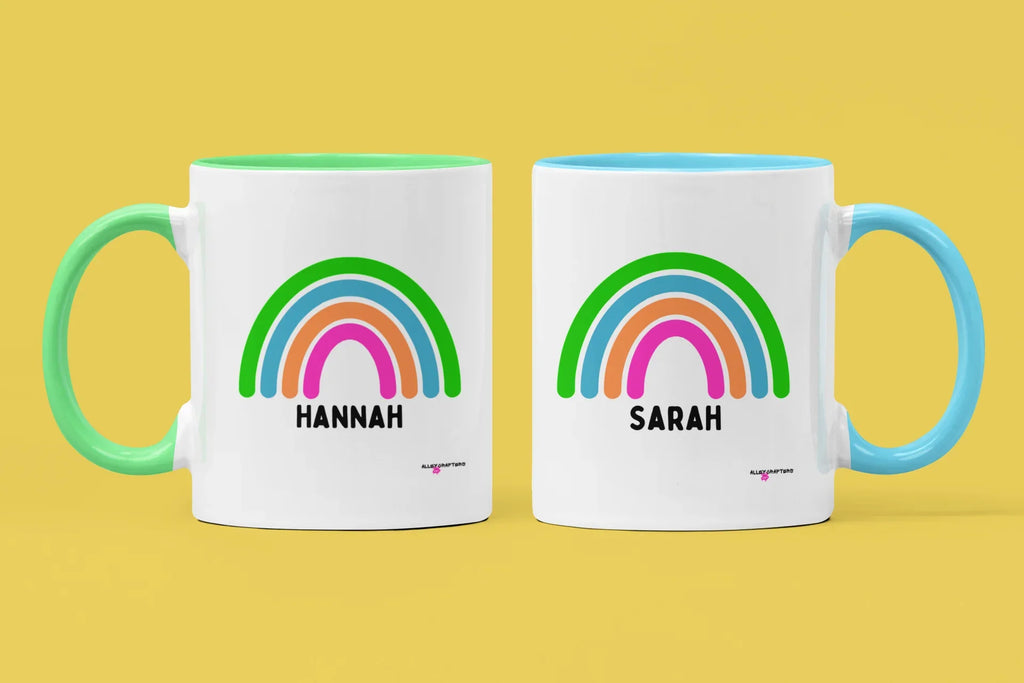 Pair of personalised rainbow mugs with names Hannah and Sarah, mint and yellow handles.