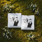 Pair of white personalised hoodies on grass, couple line-art graphic with names underneath