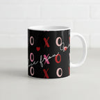 Black ceramic mug with pink/red XO hearts and “Love” script across the front