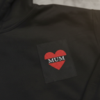 Black hoodie with red heart patch and stitched 'MUM' lettering at back