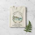 Beige T-shirt with scenic landscape wreath graphic and “Alice & James” since 2018
