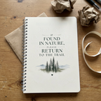 Ivory nature notebook with spiral binding on wooden surface, with return message and forest graphic.