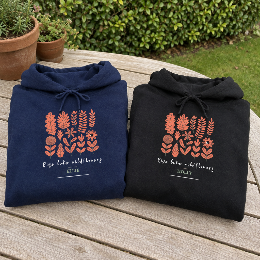 Navy and black Wildflowers hoodies folded together in a garden