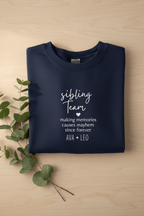 Navy crewneck sweatshirt folded with “sibling team” quote print in white ink