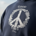 Navy unisex hoodie close-up of embroidered floral peace sign and "GOOD VIBES" text