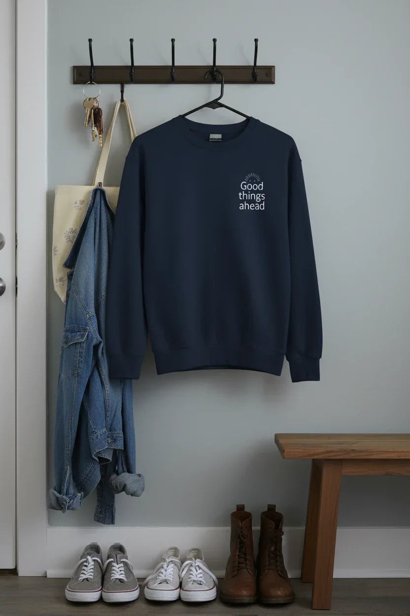 Navy crewneck sweatshirt hanging on a wooden hanger with chest logo
