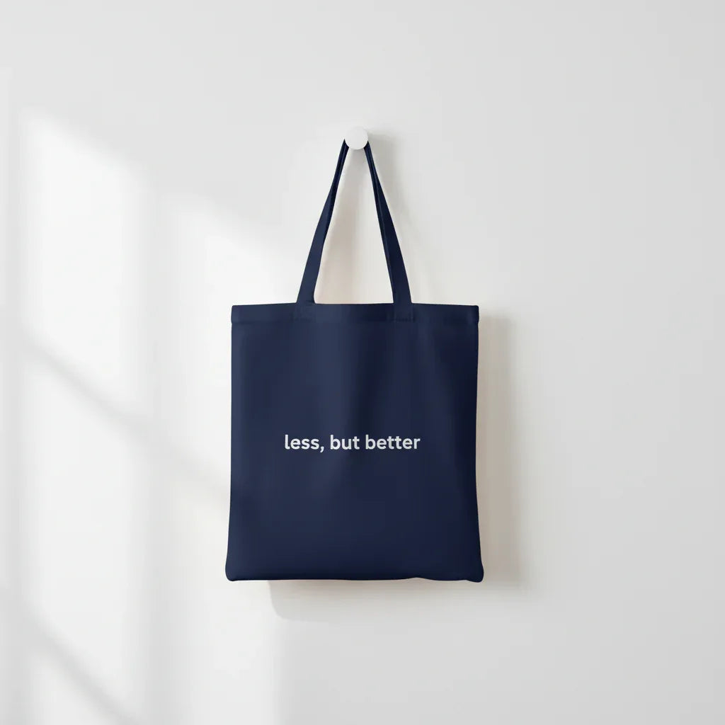 Navy cotton tote bag with long handles and 'less, but better' front print.