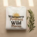 White crewneck sweatshirt with “Wild hearts Protect Wild Places” graphic on chest