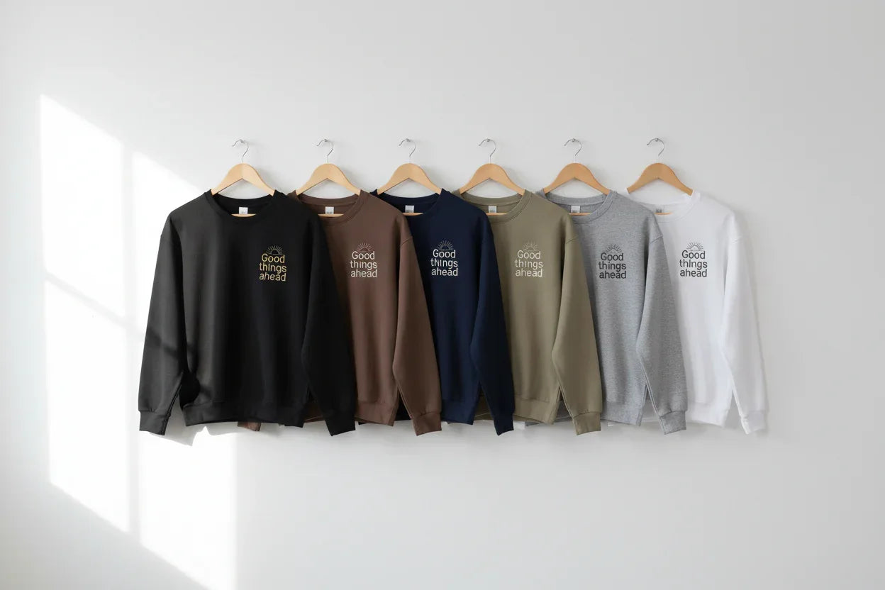Crewneck sweatshirts on hangers in black, brown, navy, olive, gray, and white