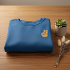 Royal blue crewneck sweatshirt folded with peace-sign hand embroidery patch